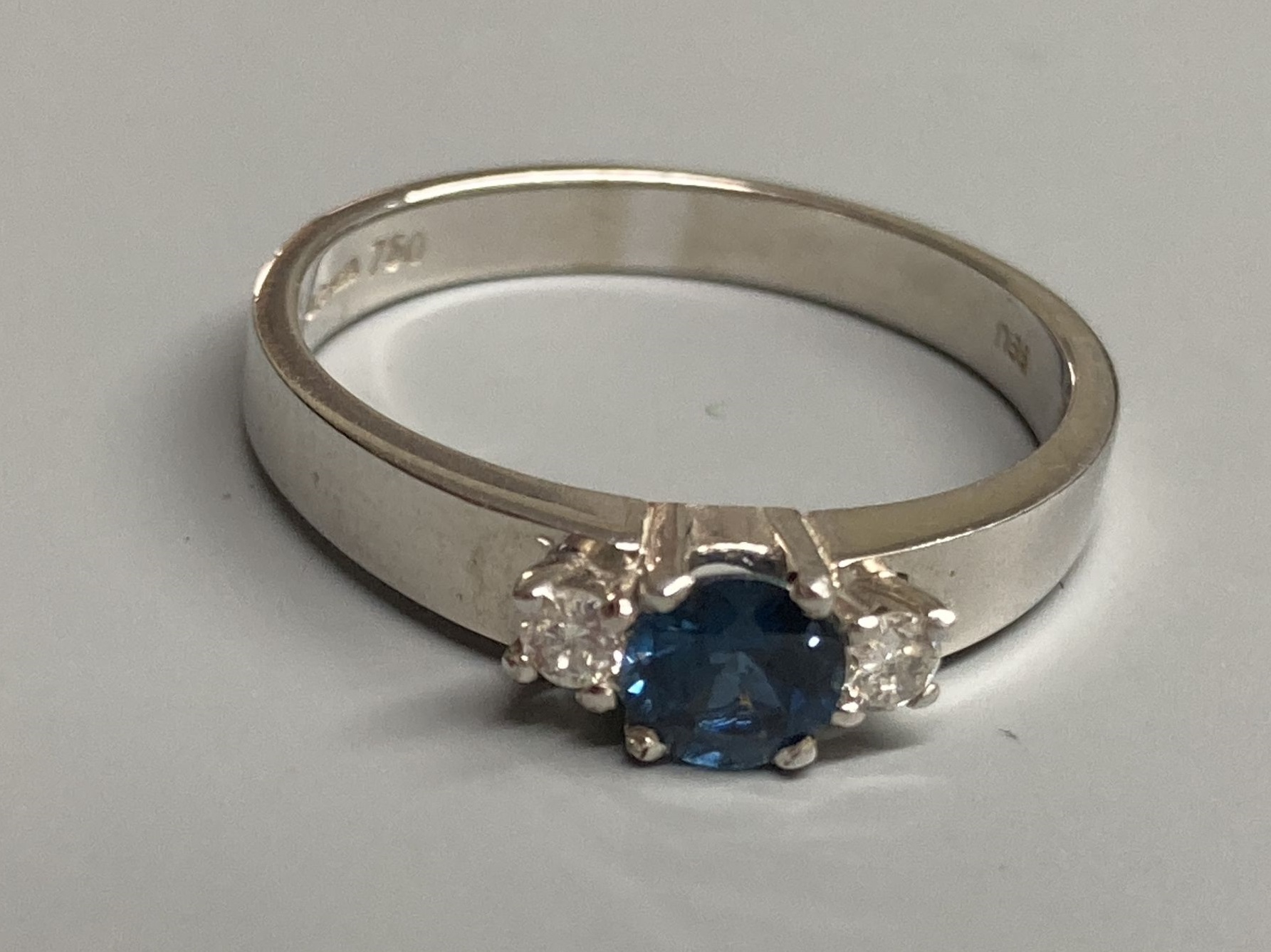 A modern 18ct white gold, sapphire and diamond set three stone ring, size N/O, gross 3.2 grams.